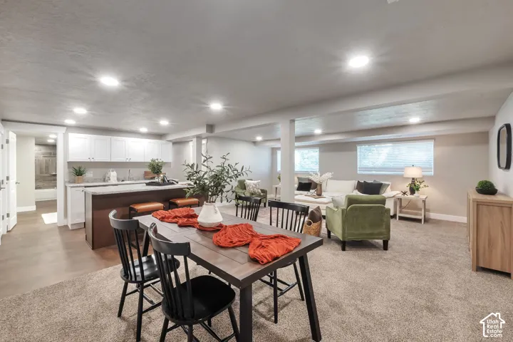 Open-concept living area featuring recessed lighting, a built-in kitchen island with seating, white cabinetry, and light-toned flooring