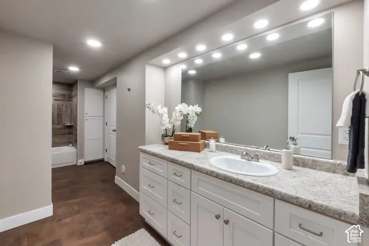 White vanity with integrated sink, speckled countertop, and full-width mirror