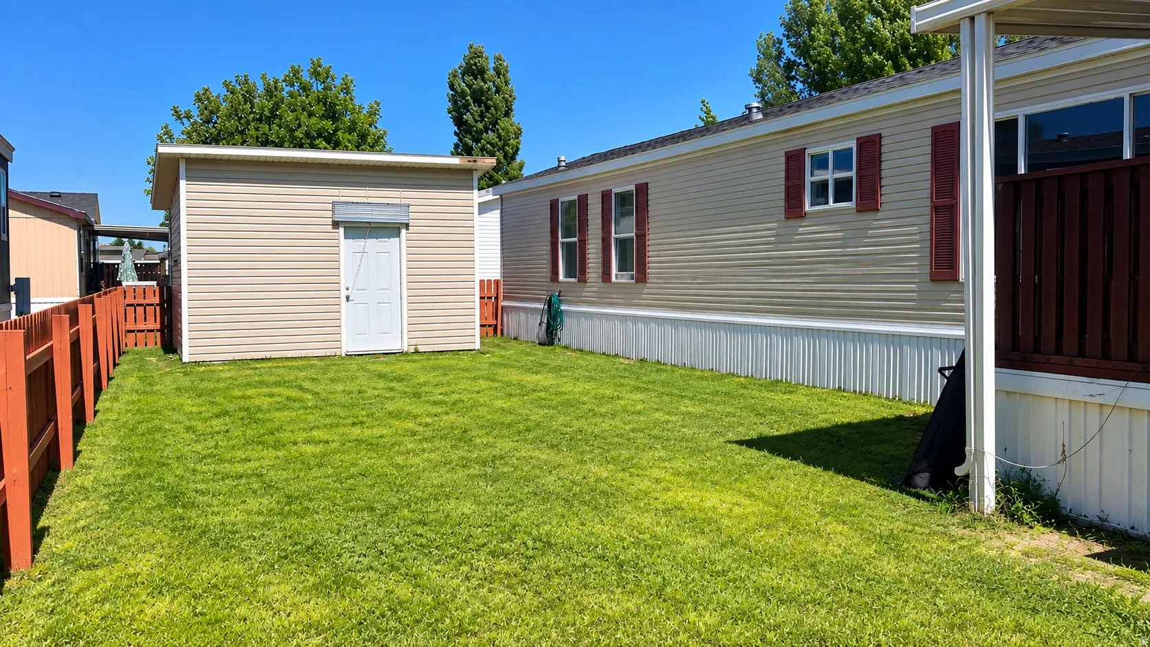 Expansive grassy yard with wood fencing, a dedicated storage shed, and exterior siding