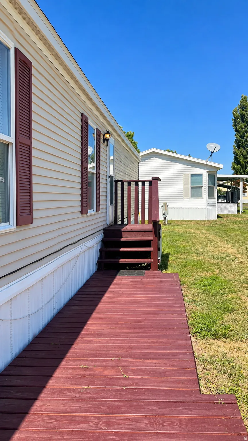 Side exterior with cream-colored siding, red shutters, and an outdoor wall light fixture