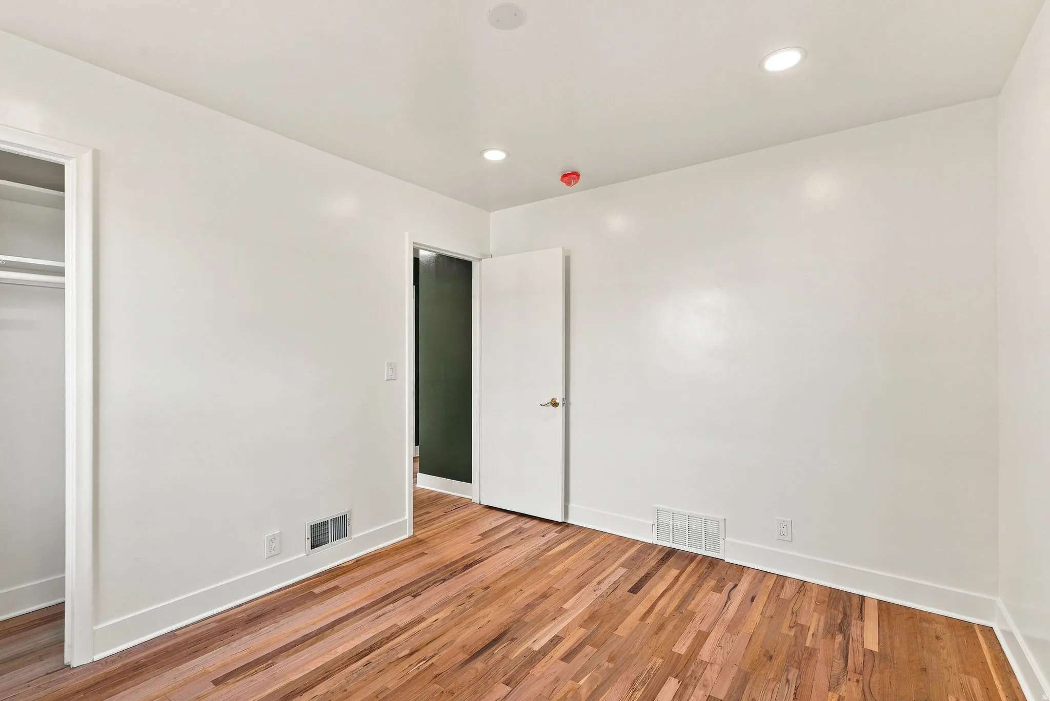 Hardwood flooring, recessed lighting, white walls, and white trim
