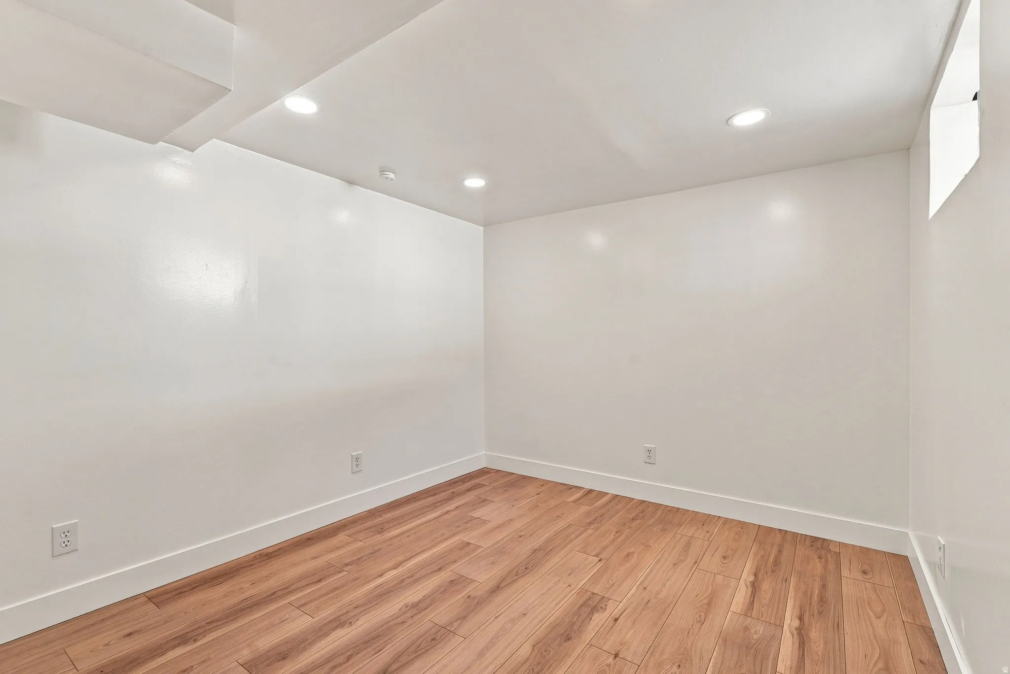 Recessed lighting, wood-finish flooring, white walls, and bright white trim