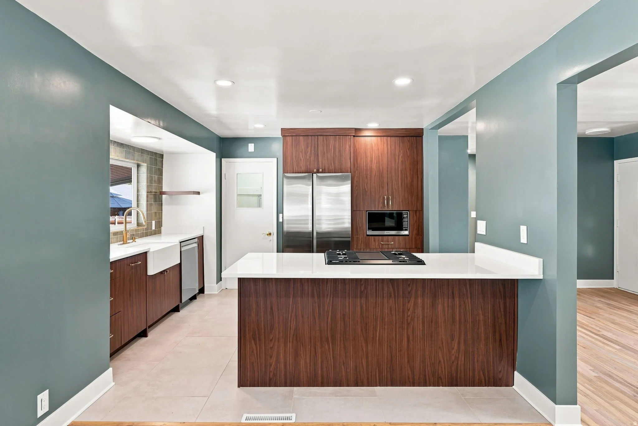Kitchen featuring wood-finish cabinetry, stainless steel appliances, a white farmhouse sink, a gas cooktop, and a white countertop