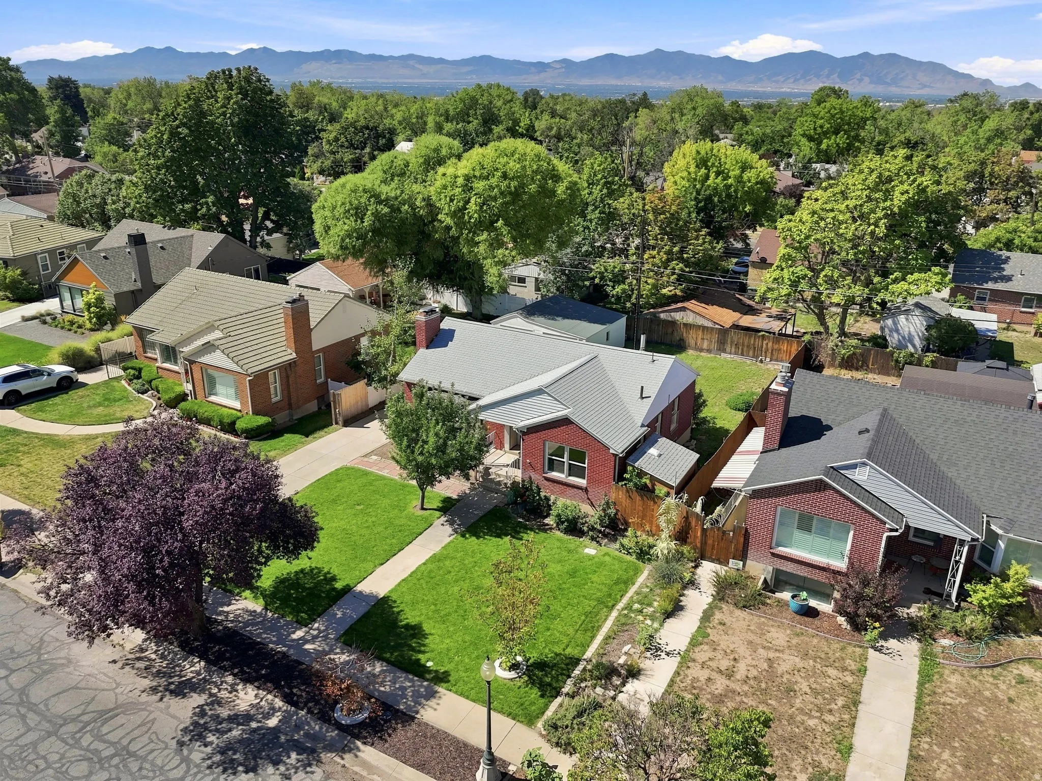 Red brick residence with a gabled roof, mature landscaping, and a manicured lawn