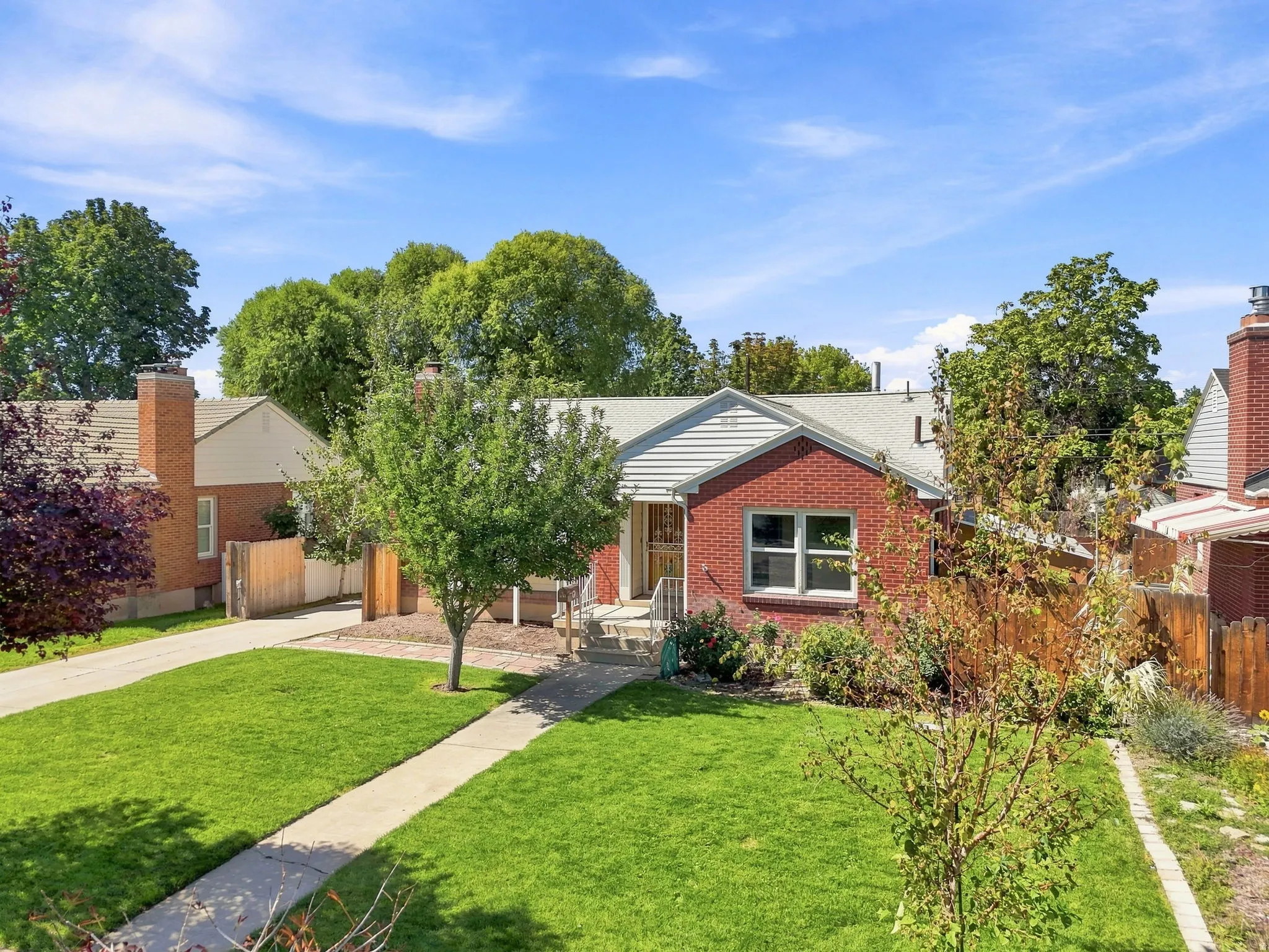 Brick exterior with white trim, a gabled roof, and a mature front yard