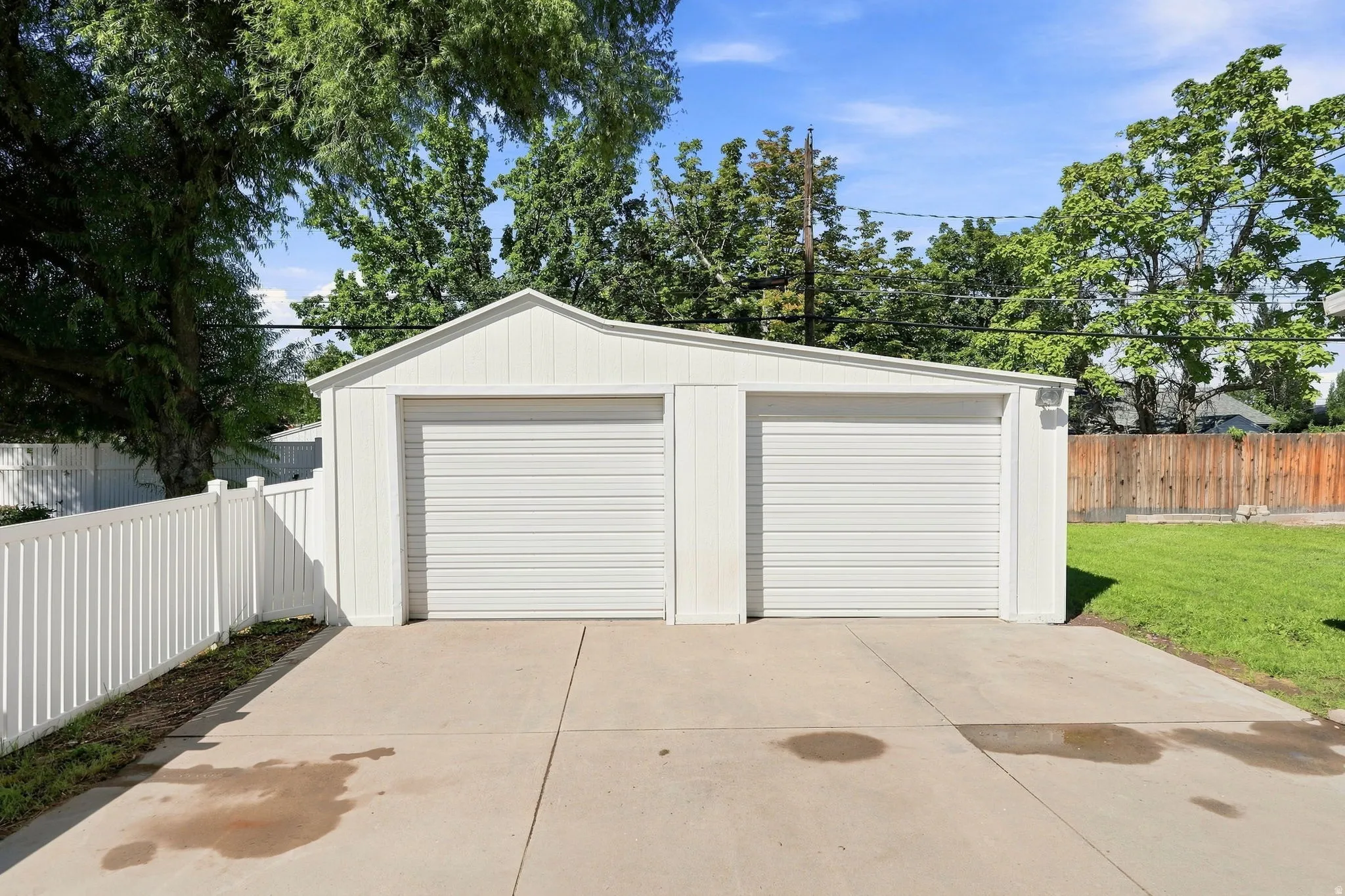 Two-car detached garage with white siding and a concrete driveway