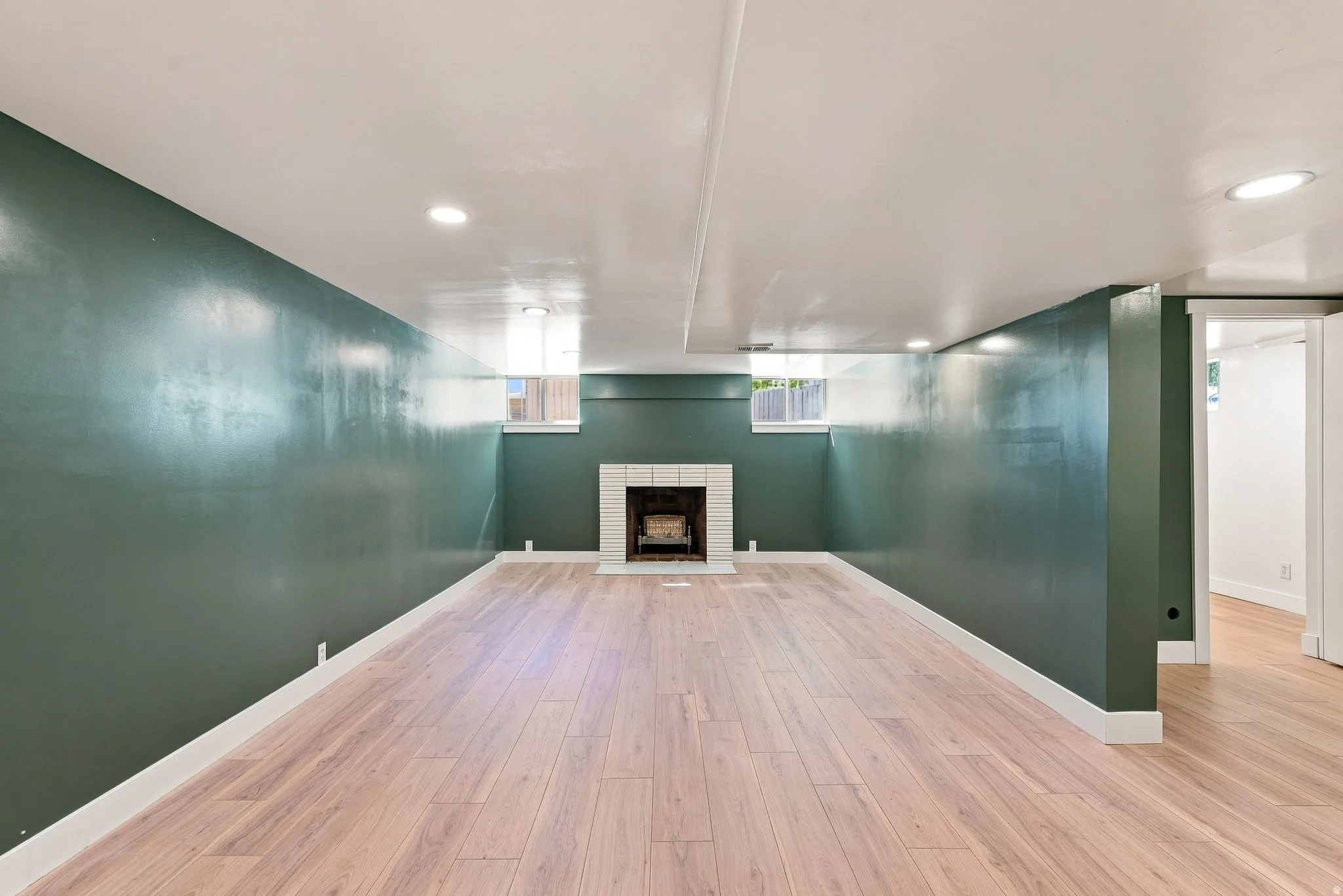 Expansive room featuring wood-finish flooring, a white tile fireplace, and recessed lighting