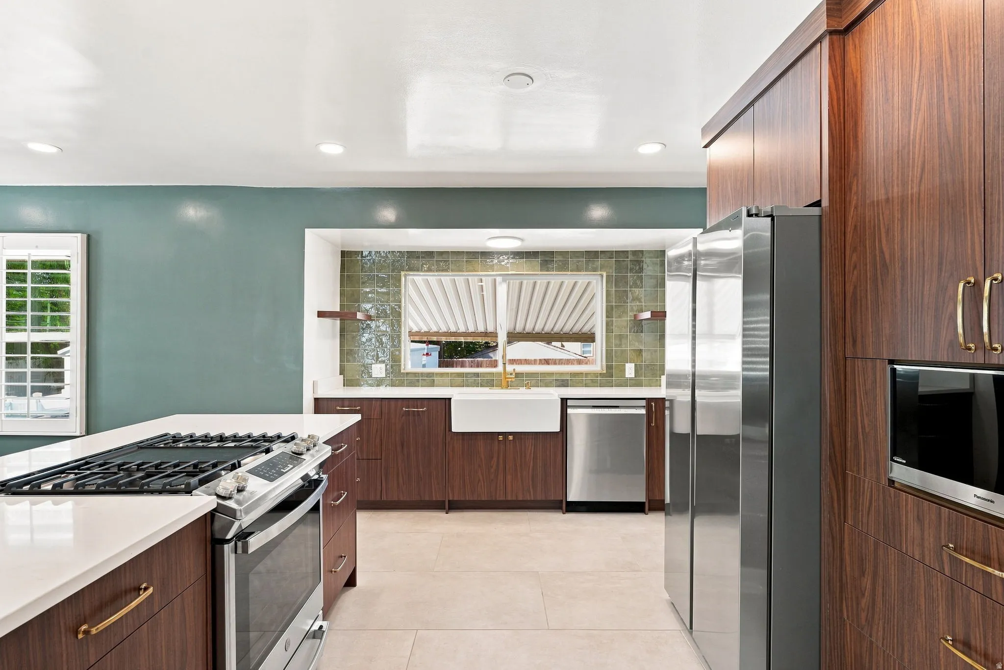 Contemporary kitchen featuring wood-finish cabinetry, stainless steel appliances, a center island with cooktop, and a farmhouse sink