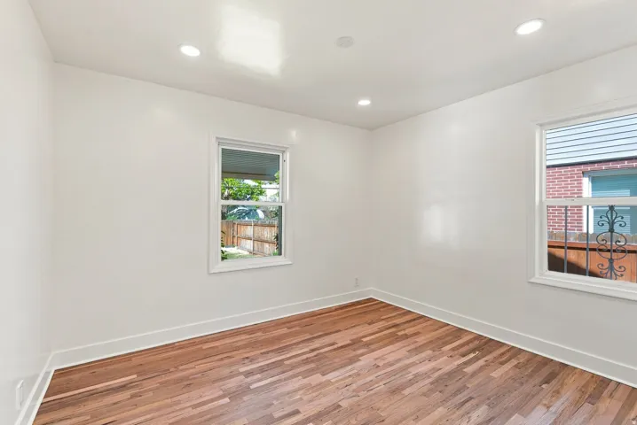 Recessed lighting, wood-finish flooring, white walls, and two windows with white frames