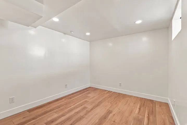Recessed lighting, wood-finish flooring, white walls, and bright white trim