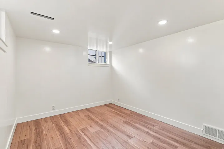Hardwood-style flooring, recessed lighting, white walls, and a casement window