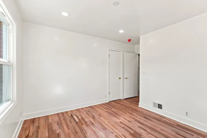 Hardwood flooring, recessed lighting, white walls, and a window with white trim