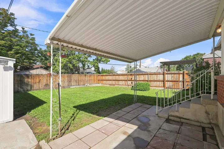 Covered patio with metal awning, concrete slab, and wrought iron railing
