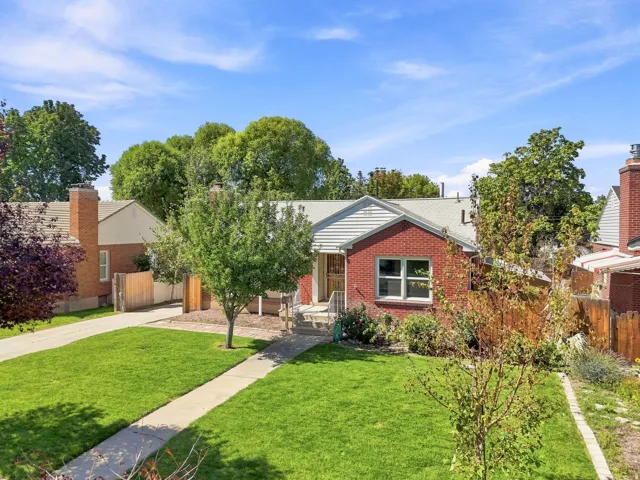 Brick exterior with white trim, a gabled roof, and a mature front yard