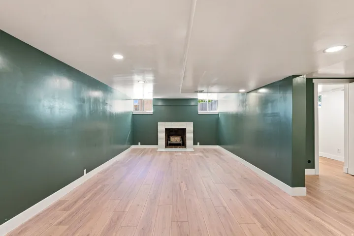 Expansive room featuring wood-finish flooring, a white tile fireplace, and recessed lighting