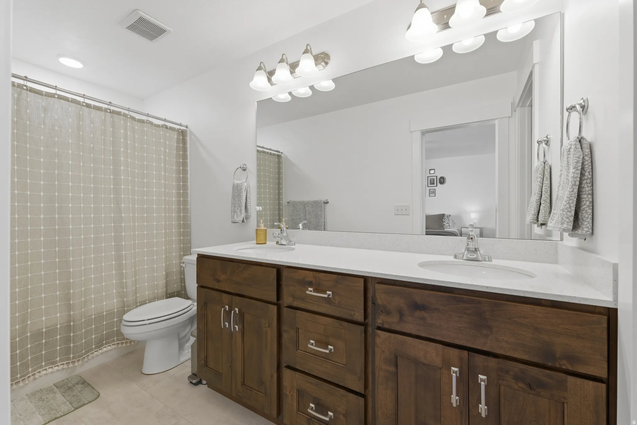 Dual vanity with wood-finish cabinetry, white countertop, and integrated sinks