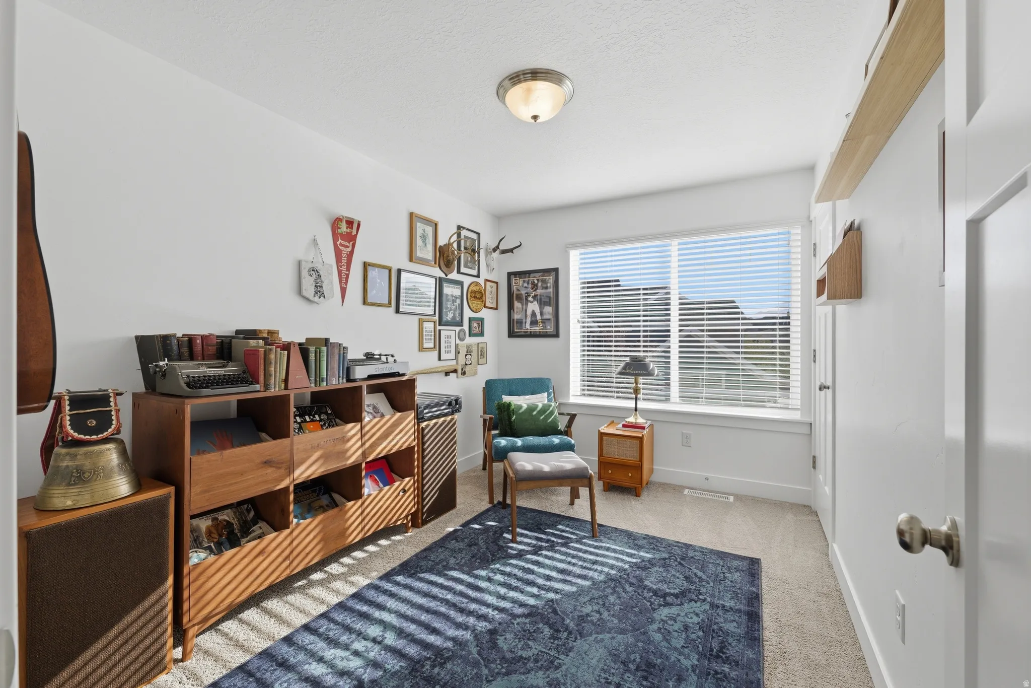 Recessed window with blinds, overhead flush mount lighting, light-toned carpet flooring, and a white wall finish