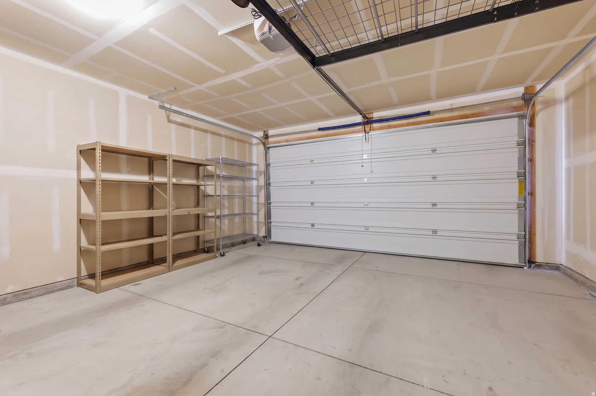 Attached garage with a sectional overhead door, concrete flooring, and an overhead storage rack