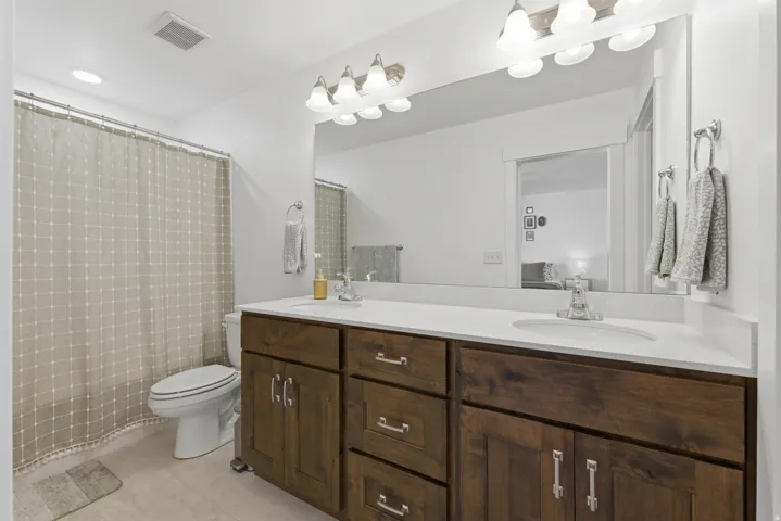 Dual vanity with wood-finish cabinetry, white countertop, and integrated sinks
