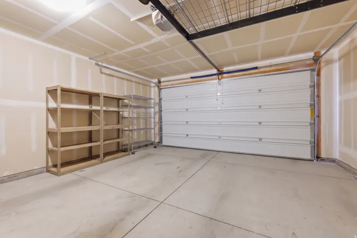 Attached garage with a sectional overhead door, concrete flooring, and an overhead storage rack
