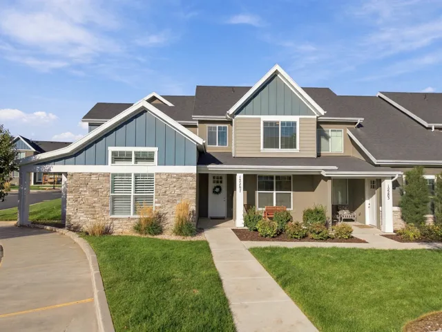 Multi-level townhouse with stone veneer accents, blue vertical siding, and a covered entryway