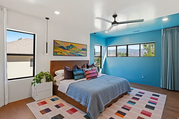Wood-finish flooring with recessed lighting, black framed windows, and a ceiling fan