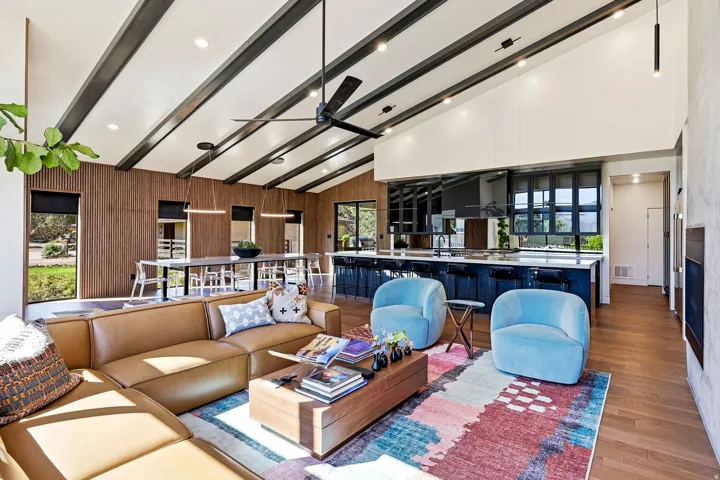 Vaulted ceiling with exposed beams, wood-finish flooring, recessed lighting, and a large central island with seating