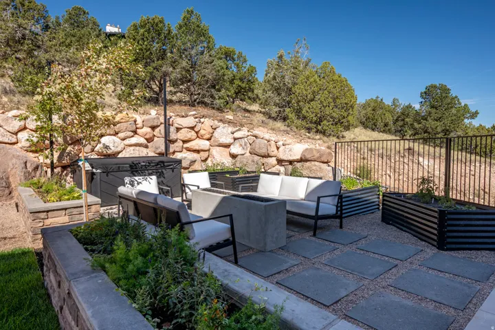 Outdoor patio featuring square pavers, gravel ground cover, a rock retaining wall, and built-in planters