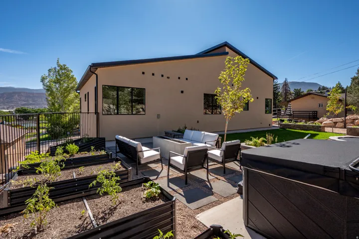 Rear exterior with stucco finish, black-framed windows, and a paved patio area