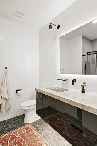 Contemporary vanity with an integrated basin, stone countertop, gloss black cabinetry, and a wall-mounted faucet