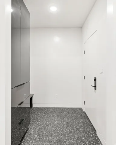Recessed ceiling lighting, built-in storage cabinetry with dark hardware, terrazzo flooring, and a white interior door with matte black hardware