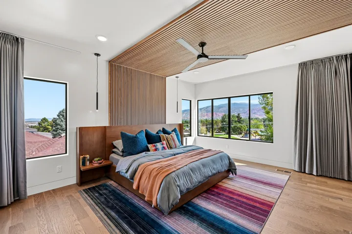 Wood-finish flooring, accent wall with vertical wood paneling, wood-slat ceiling detail, recessed lighting, and expansive windows