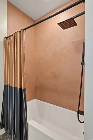 Soaking tub with a rain shower head, hand-held shower, and matte black fixtures