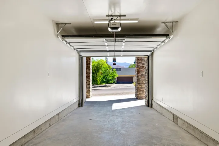 Garage with an automatic opener, exposed track system, and concrete flooring