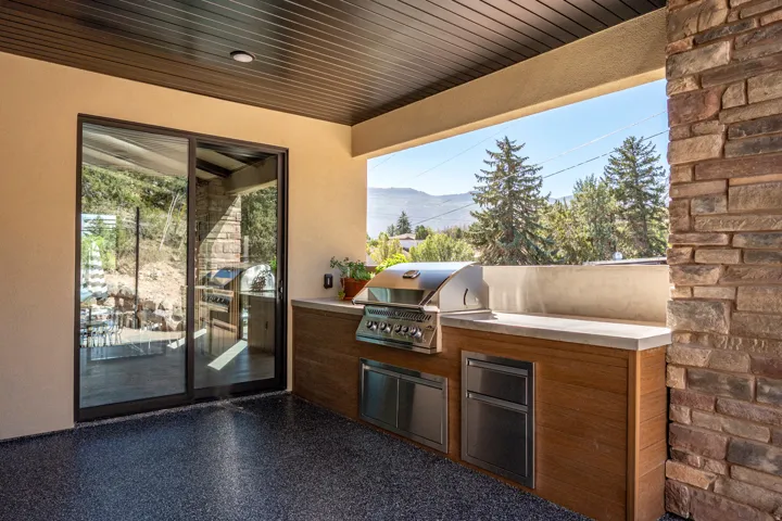Outdoor kitchen with built-in stainless steel grill, integrated refrigeration, and a concrete countertop