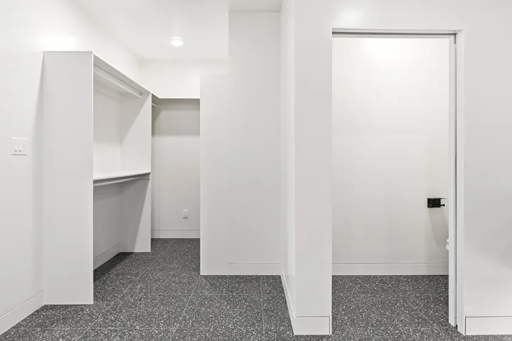 Walk-in closet with built-in shelving, hanging rods, recessed lighting, and gray speckled flooring