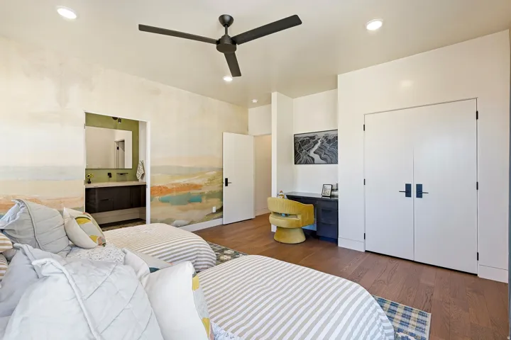 Recessed ceiling lighting, ceiling fan, wood-finish flooring, built-in desk, and double doors with matte black hardware