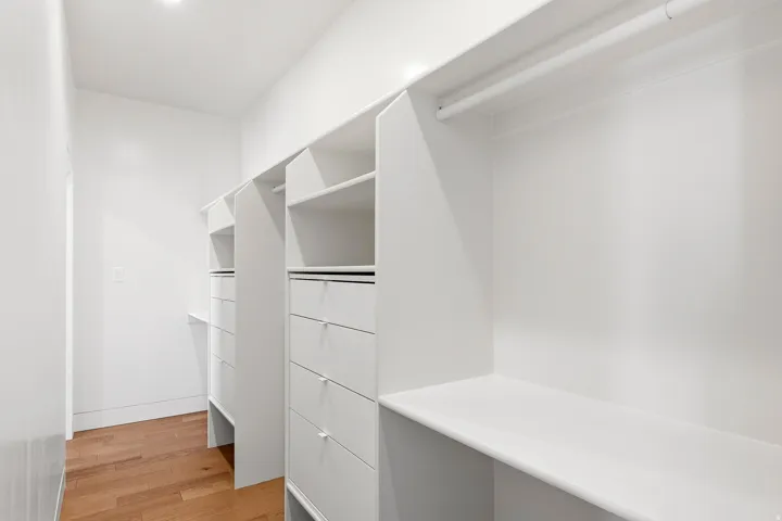 Walk-in closet featuring custom built-ins, multiple shelving units, integrated drawers, and ample hanging space