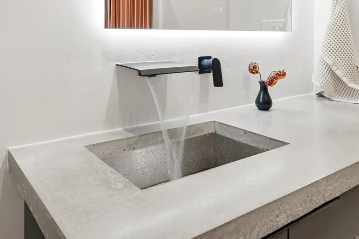 Integrated concrete countertop and sink with a matte black waterfall faucet