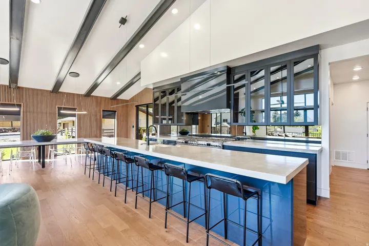 Spacious kitchen featuring a large central island with a light-toned countertop, a range with an integrated hood, and dark-framed upper cabinetry