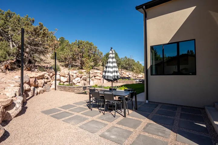 Patio featuring paver stones, gravel surfacing, a stucco exterior, and a rock retaining wall
