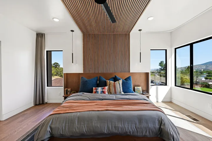 Wood-finish flooring, recessed lighting, and a slatted wood ceiling feature with an integrated ceiling fan