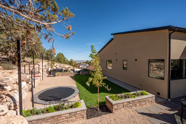 Expansive backyard featuring a manicured lawn, built-in trampoline, and stone retaining walls