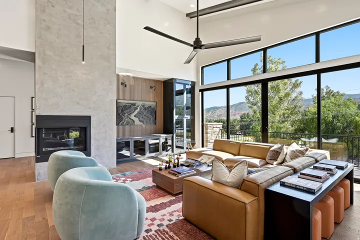Vaulted ceilings with a large ceiling fan, floor-to-ceiling windows, a built-in fireplace, and wood-finish flooring