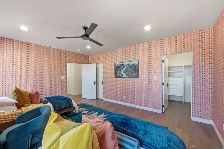 Room featuring patterned wallpaper, recessed lighting, wood-finish flooring, a ceiling fan, and a built-in closet with shelving