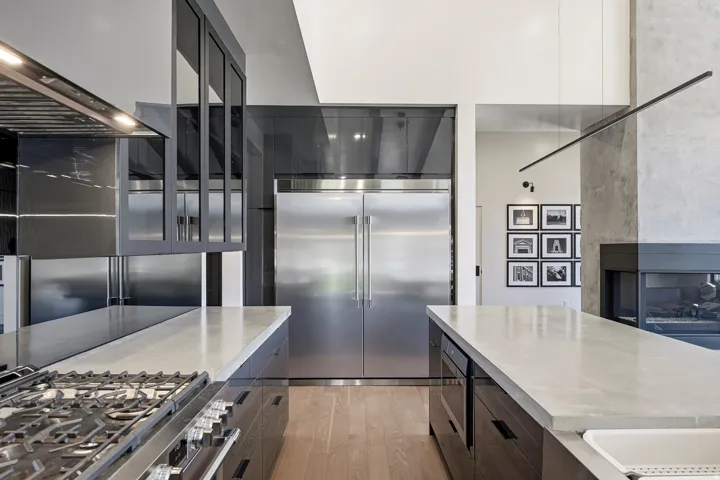 Gourmet kitchen with stainless steel appliances, dual islands with light-toned countertops, professional-grade gas range, and wood-finish flooring