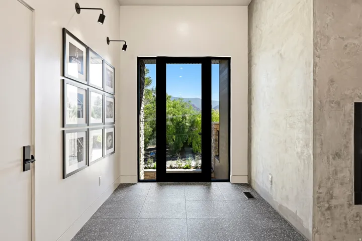 Full-height exterior door, terrazzo-style flooring, white walls, and a textured accent wall