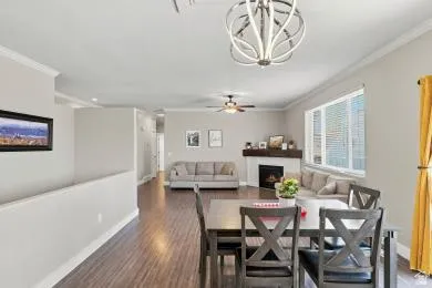 Open-concept living area featuring a decorative chandelier, wood-finish flooring, recessed lighting, a built-in fireplace with a mantel, and a multi-pane window