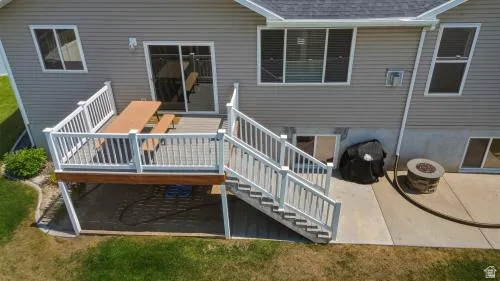 Rear exterior featuring a multi-level deck, sliding glass door, and a ground-level patio with a built-in fire pit