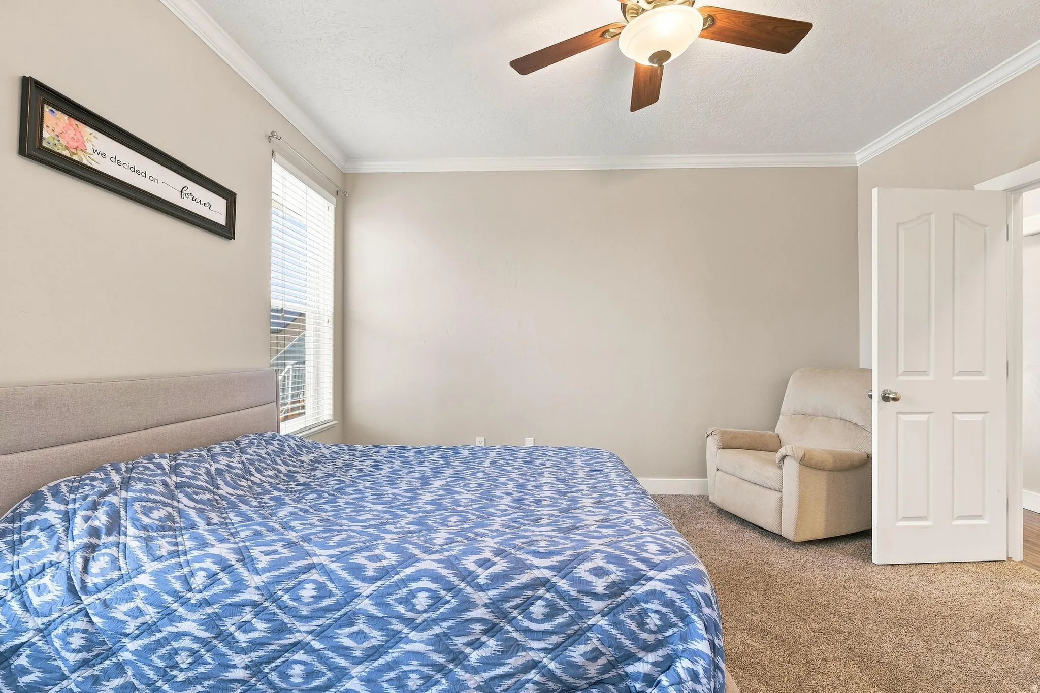 Primary Bedroom! Carpeted room featuring a ceiling fan with light fixture, window with blinds, and painted walls with crown molding